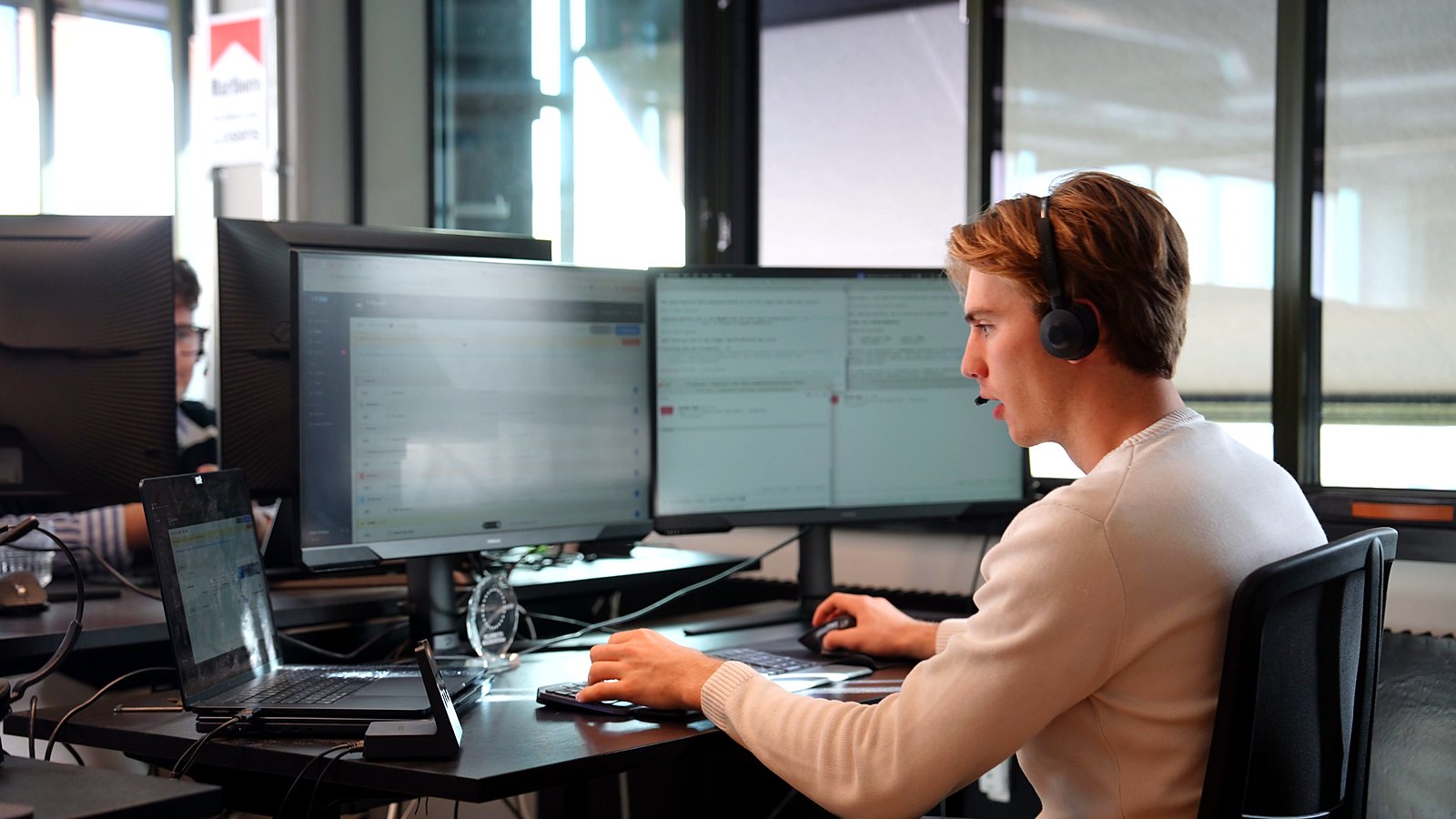 SDR med headset ved to skærme midt i arbejdet