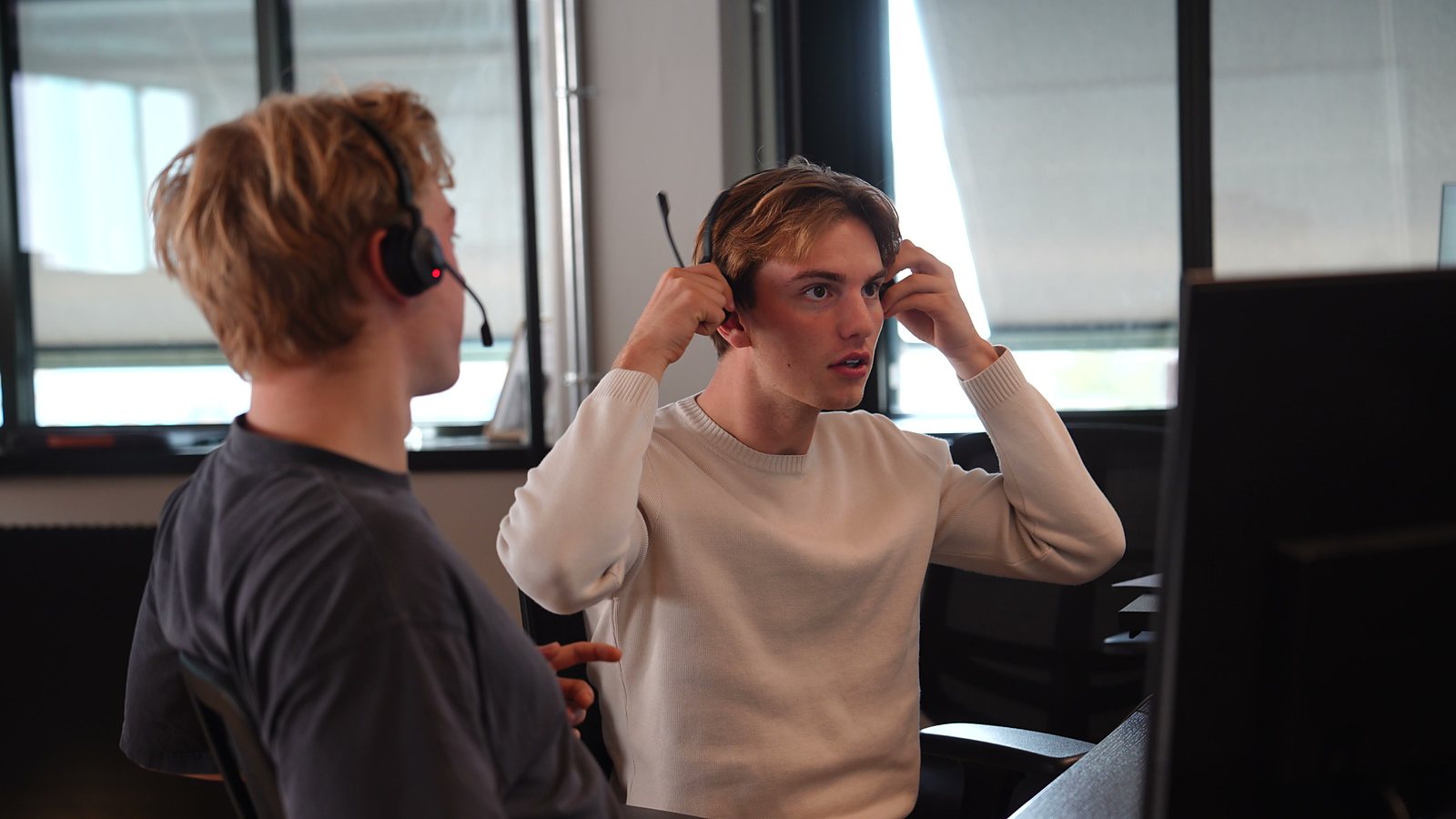 Two SDRs at their screens, one putting on a headset