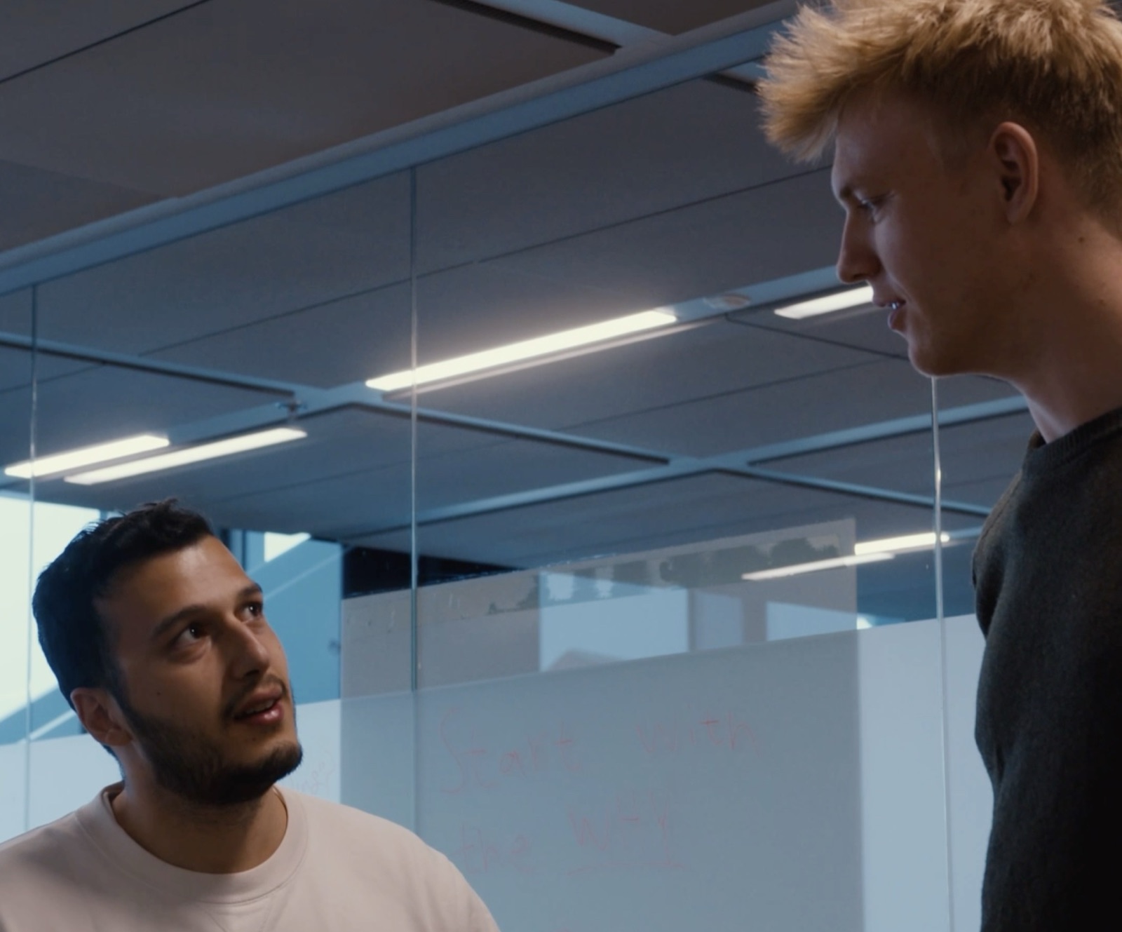 Two people from Fullview talking by the glass wall in the office