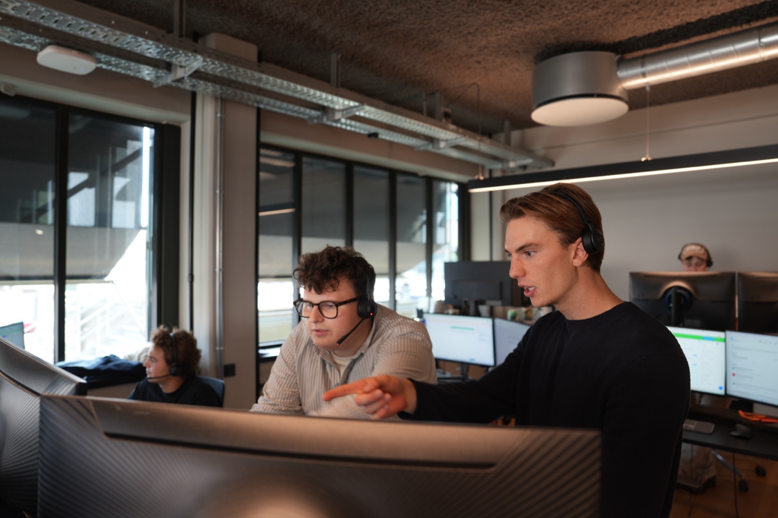 Two colleagues at one screen, one pointing at something in the pipeline