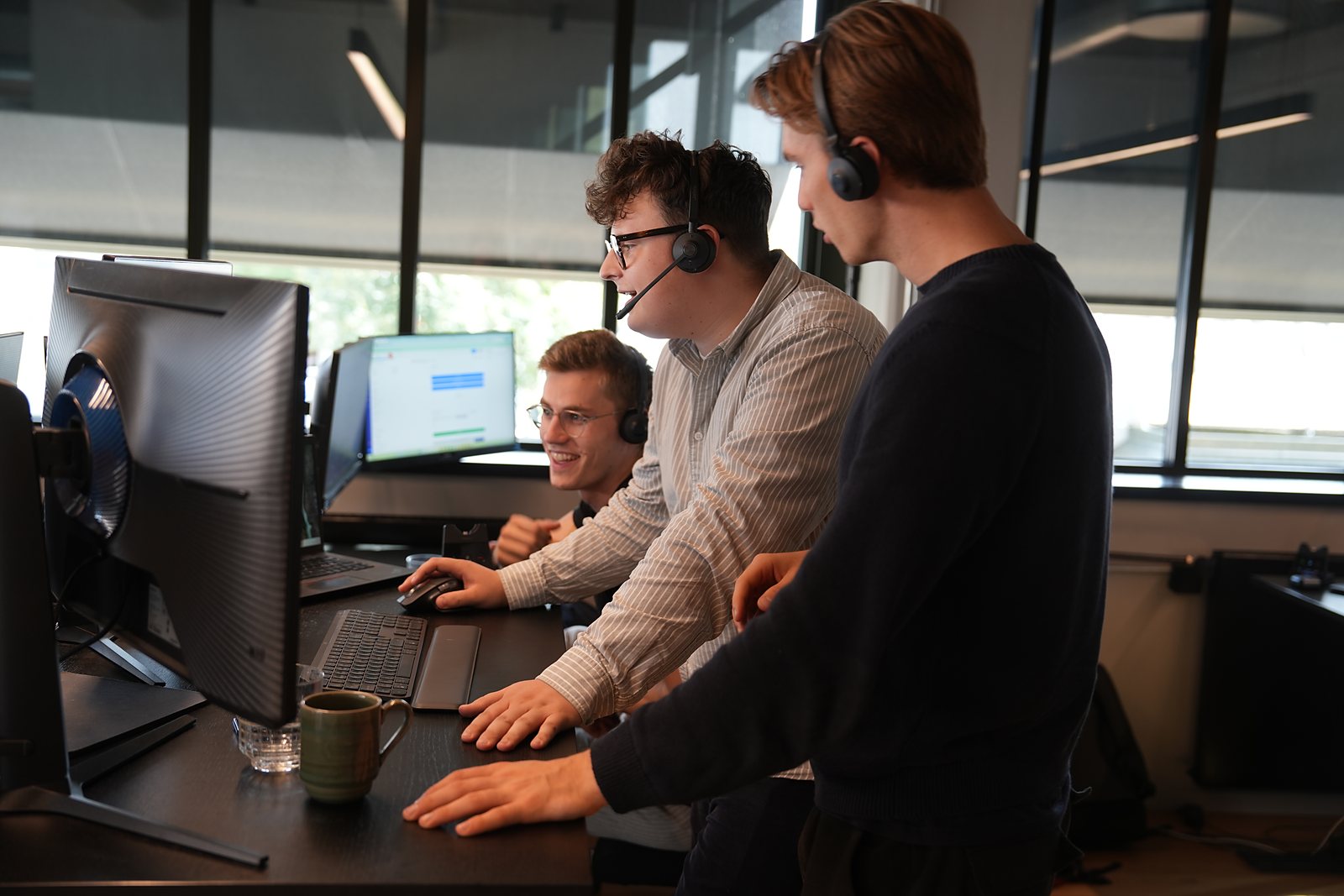 Three SDRs in headsets gathered round the same screen