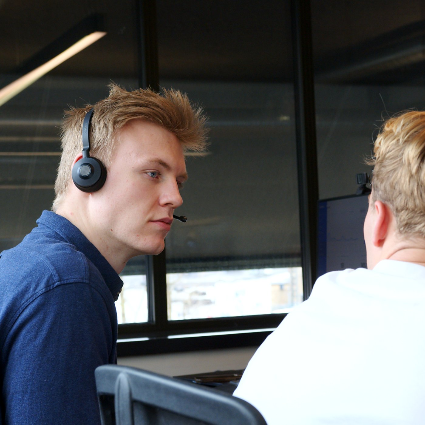 SDR with a headset in a huddle with a colleague at the screen