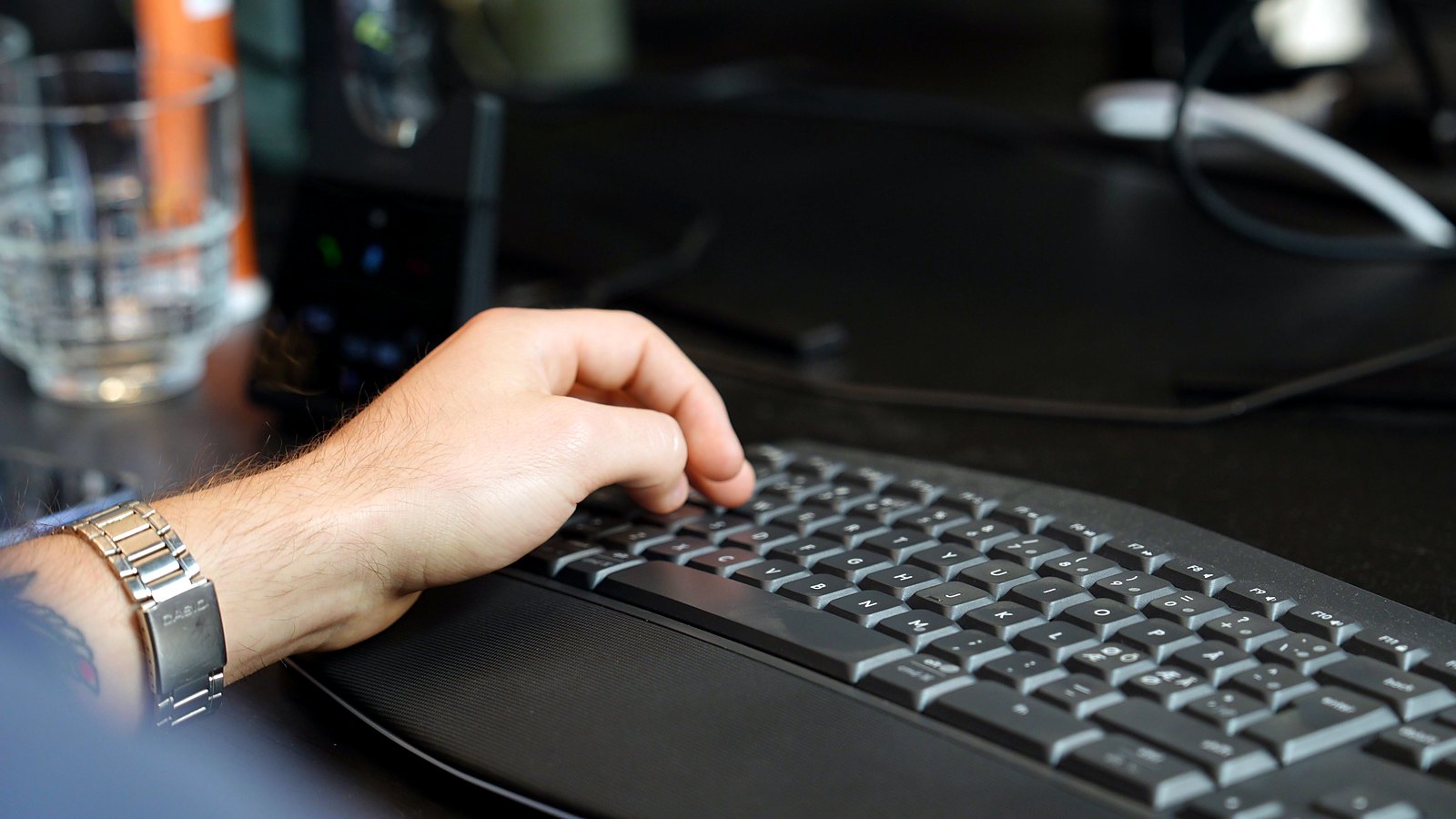 Hånd på tastaturet ved et ryddeligt skrivebord