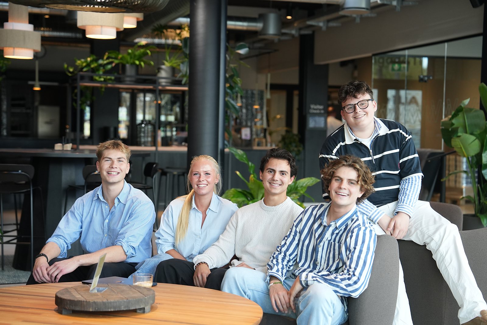 Five of the team together in the lounge, all smiling at the camera