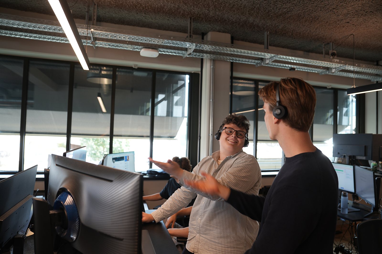 Two colleagues in headsets mid-conversation at the screen